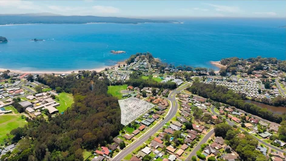 Aerial photograph of the Batemans Bay site at Sunshine Bay with the concept lot layout overlaid, looking north over the town to the bay and the ocean beyond
